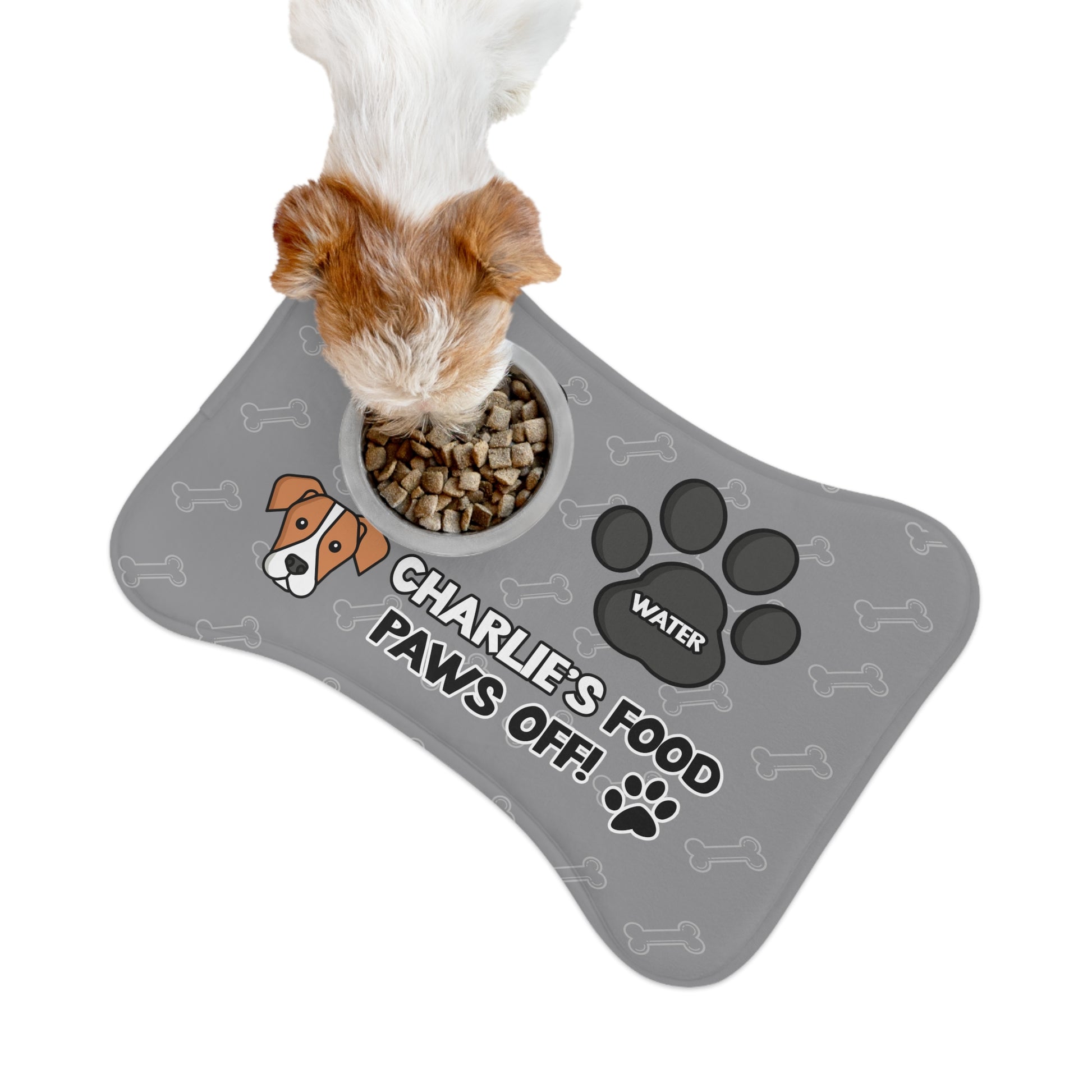 a dog eating over a personalized dog food mat with the a bone shape, two big paws with the words "Food" and "Water" at the top. And the face of a cute dog next to the words "Dog's Food Paws Off!". Color of the pet feeding mat is grey