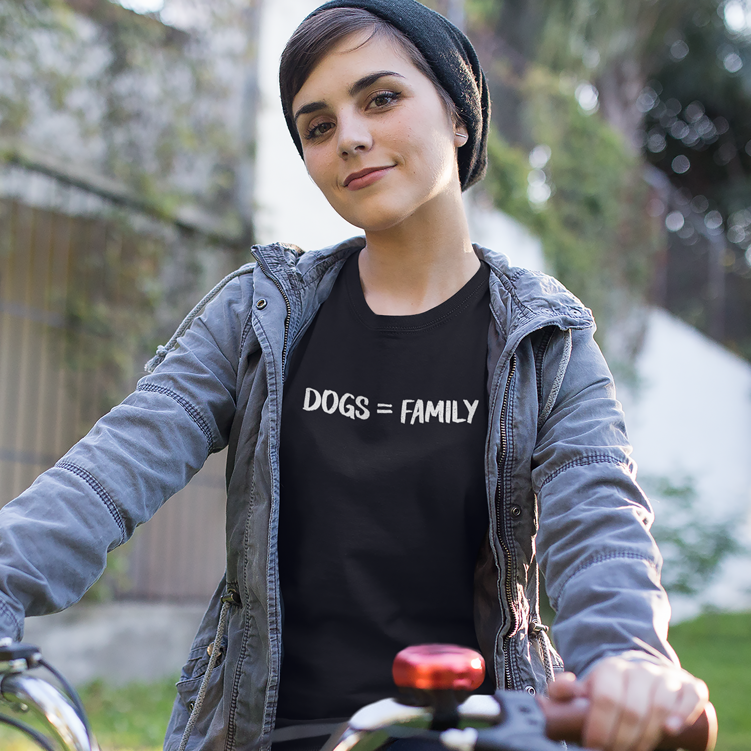 A beautiful girl riding a bike and wearing a black shirt with the message "Dogs = Family"