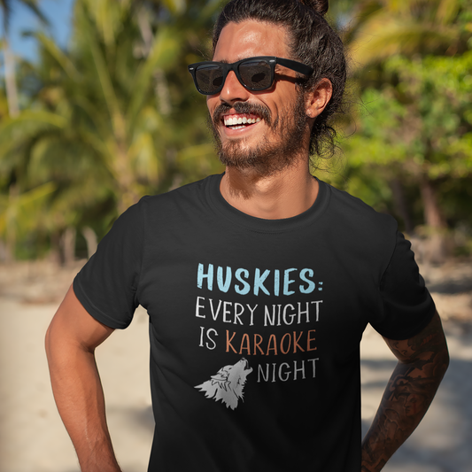 A man with glasses wearing a T shirt with the design: "HUSKIES: Every Night Is Karaoke Night." Shirt Color is black